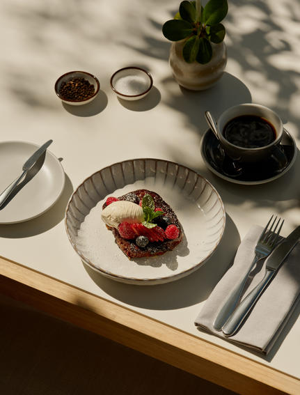 Breakfast at Amanyara with plated fruit dish, coffee cups, and cutlery on white linen.