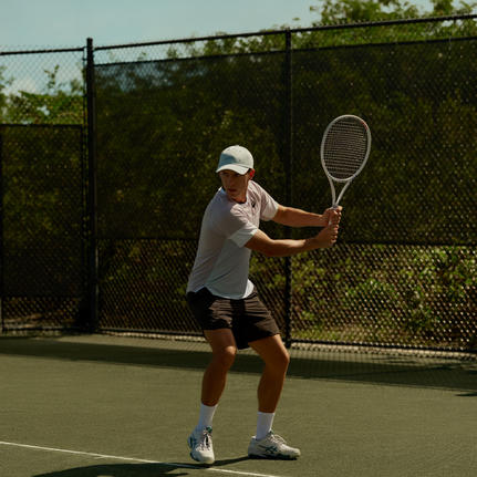 Joueur de tennis en position de service sur un court à Amanyara, resort aux Turks-et-Caïques.