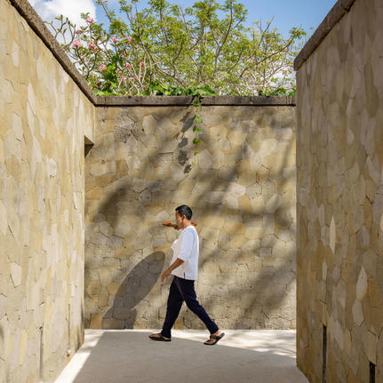 Private butler walking through shaded courtyard at Aman Villas at Nusa Dua, Indonesia.