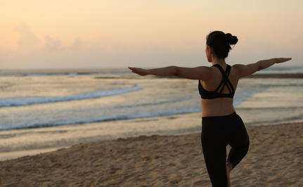 Woman holding surfboard at dawn on Nusa Dua beach, Bali.