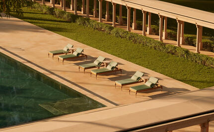 Sunloungers arranged along the poolside at Amanbagh, India, with manicured lawn beyond.