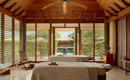 Salle de spa sereine à Amanyara avec baie vitrée surplombant les jardins tropicaux.