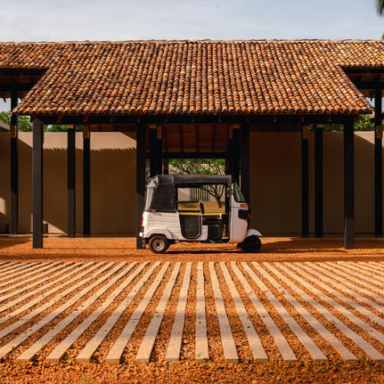 Vintage car parked beneath a wooden pavilion with terracotta roof at Amanwella, Sri Lanka.