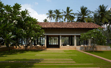 Amanwella lounge pavilion with terracotta roof, surrounded by manicured lawns and tropical palms.