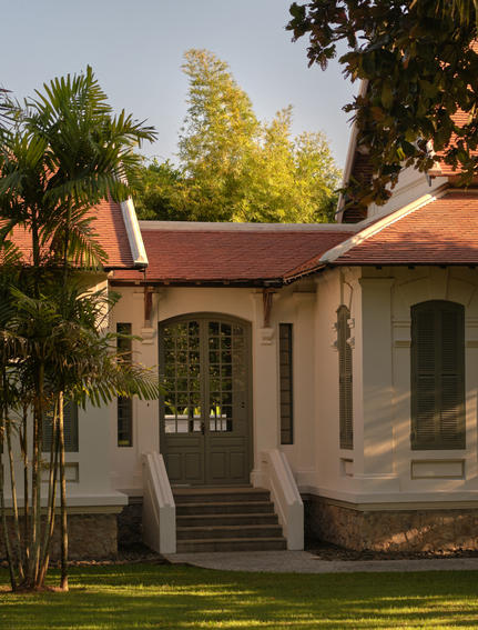 Khan Pool Suite entrance at Amantaka, featuring terracotta roof and stone exterior among lush gardens.