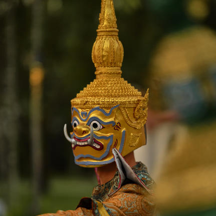 Close-up of a gilded Lao masked dance drama figure at Amantaka's poolside dinner performance.