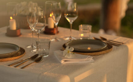 Intimate dinner table setting at Amantaka with candlelit place settings and glassware.