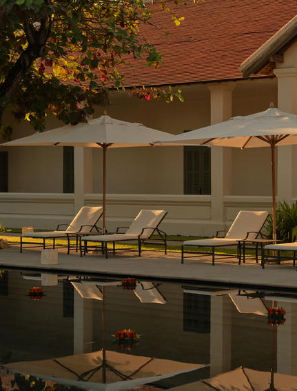 Candlelit floats during Loy Krathong ceremony at Amantaka's pool terrace at dusk.