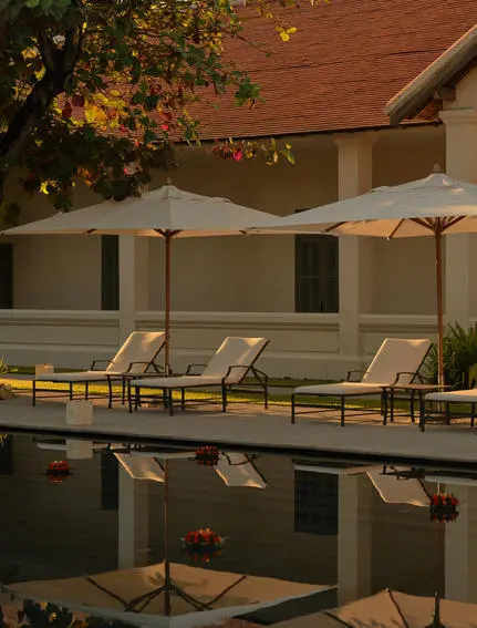 Candlelit floats during Loy Krathong ceremony at Amantaka's pool terrace at dusk.