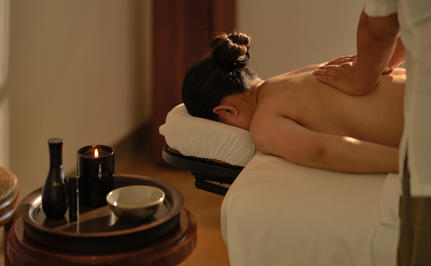 Aman spa therapist applying nourishing product to guest's arm during wellness treatment at Amantaka.