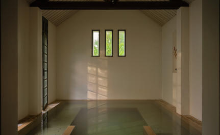 Serene bathing chamber at Amantaka with polished green floor and natural light filtering through high windows.