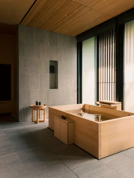 Salle de bains de la suite avec baignoire en bois massif et cloison en béton, Aman Kyoto.