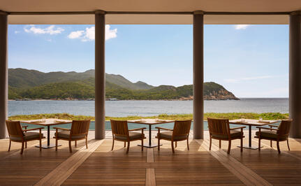 Beach Club Restaurant at Amanoi with dining tables overlooking Vietnam's coastline and mountains.