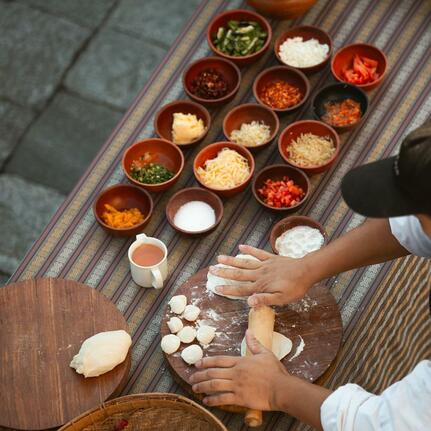 Overhead view of spices and ingredients arranged in bowls at Amankora, Punakha, with hands preparing food below.