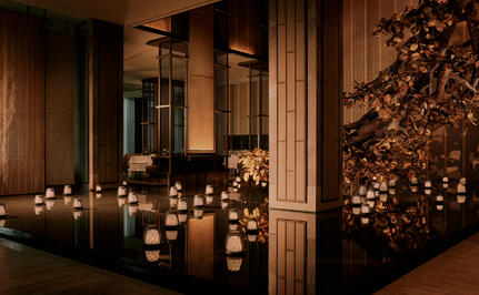 Candlelit spa sanctuary at Aman Nai Lert Bangkok, with warm golden lighting and wooden architectural details.