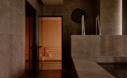 Concrete bathroom at Aman Nai Lert Bangkok with wooden door and minimal fixtures.