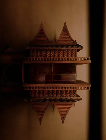 曼谷奈乐安缦酒店的传统泰式建筑模型，暖色光线映照下显现对称的尖塔设计。