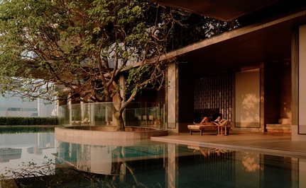 Wellness swimming pool at Aman Nai Lert Bangkok, with wooden platform beside calm water and traditional Thai architecture.