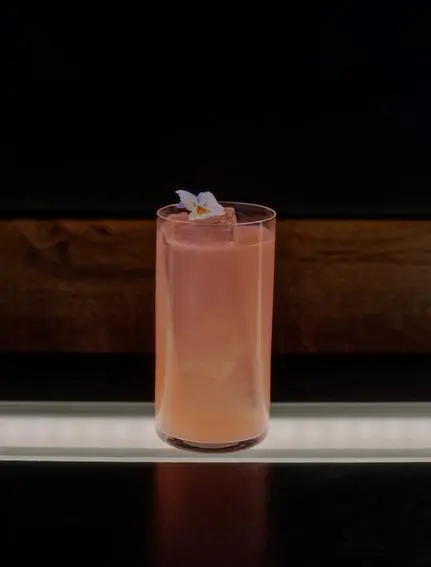 FAMP B cocktail at Aman Le Mélézin, a blush-coloured drink garnished with ice in a tall glass.