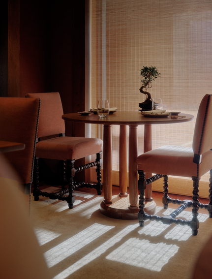 Dining area at Aman Le Mélézin with round wooden table, upholstered chairs, and geometric floor pattern.