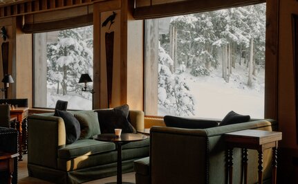 Two chairs by windows overlooking snowy landscape at Aman Le Mélézin, France.