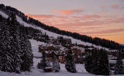 Aman Le Mélézin nestled in snowy French Alps at dusk, with warm golden light across the sky.