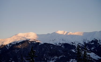 Snow-capped Alpine peaks at Aman Le Mélézin, bathed in golden morning light.