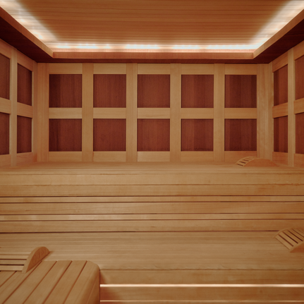 Wooden sauna interior at Aman Le Mélézin with bench seating and warm ambient lighting.