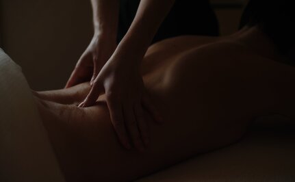 Therapist's hands performing a gentle massage on a guest's back at Aman Le Mélézin.