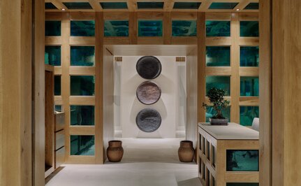 Spa reception at Aman Le Mélézin with geometric wooden shelving and central treatment door.