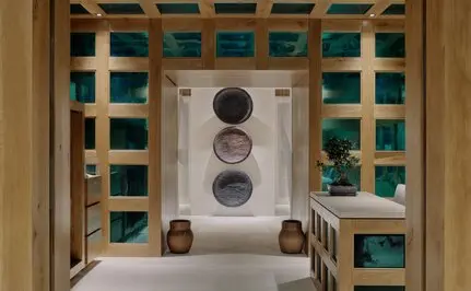Recepción del spa visto desde arriba en Aman Le Mélézin, con muebles de madera y detalles en turquesa.