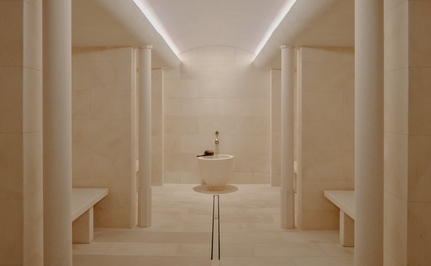 Steam room at Aman Le Mélézin with symmetrical wooden panelling and soft overhead lighting.