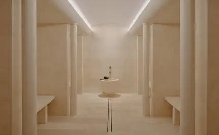 Steam room at Aman Le Mélézin with symmetrical wooden panelling and soft overhead lighting.