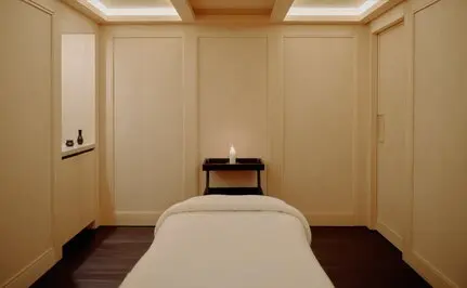 Spa wellness treatment room at Aman Le Mélézin resort with a massage table, neutral tones, and soft lighting.