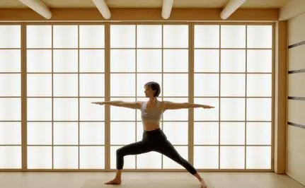 Personne pratiquant le yoga face à une grande fenêtre à carreaux, Aman Le Mélézin.