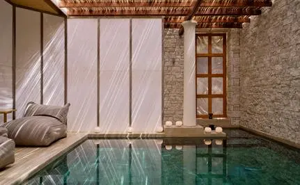 Spa and wellness pool at Amanzoe with stone walls and wooden beamed ceiling.