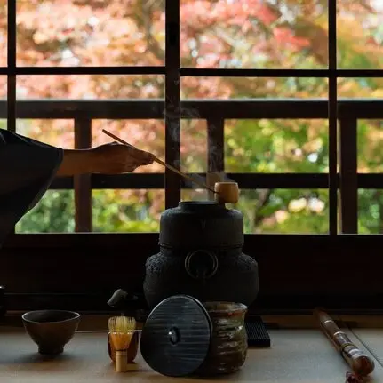Tea ceremony setup at Aman Kyoto, with traditional vessels arranged by a wooden latticed window overlooking gardens.