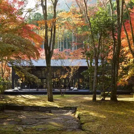 Pavilion exterior at Aman Kyoto resort surrounded by autumn foliage and tall trees.