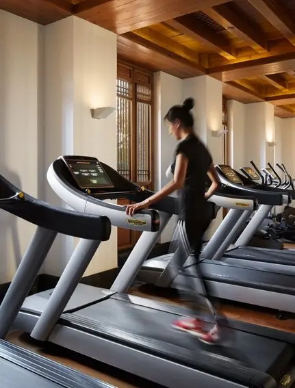 Woman running on treadmill in Amandayan's fitness centre with exposed wooden beams.