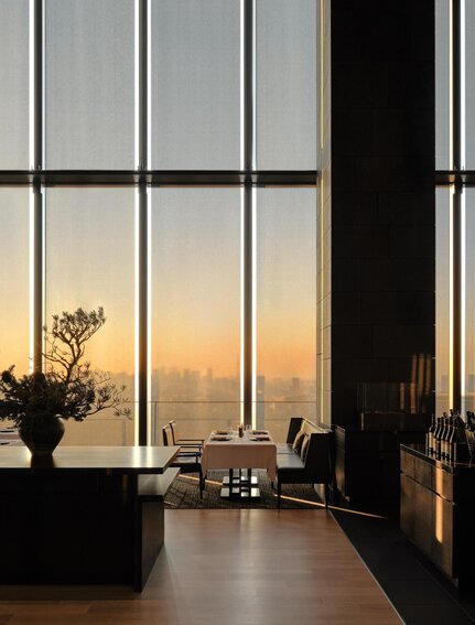 Arva interior at Aman Tokyo hotel with floor-to-ceiling windows framing sunset over the city.