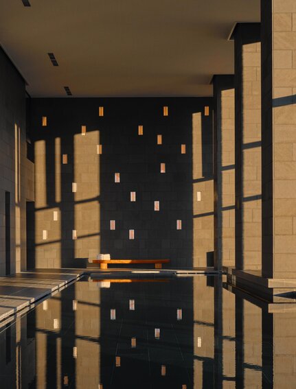 Piscina reflejada en agua tranquila con iluminación cálida en Aman Tokyo.