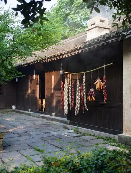 Amanfayun's steam house dining venue with dark timber façade and traditional architecture framed by green foliage.