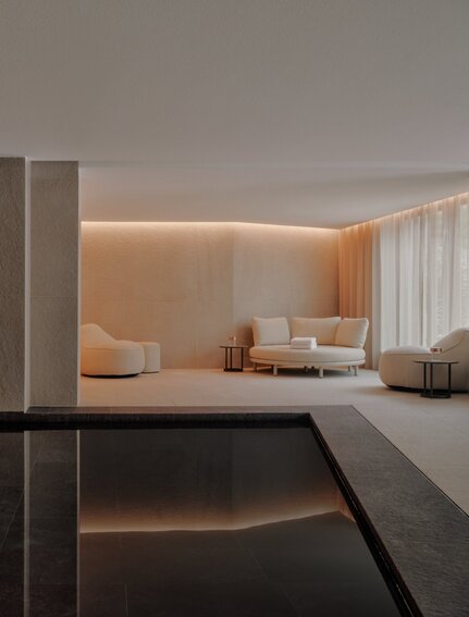 Piscina interna illuminata con vasche in marmo scuro e pareti chiare presso Aman Rosa Alpina.