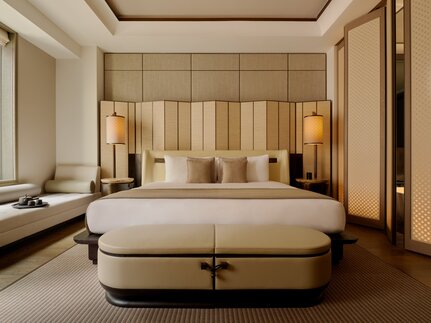 Grand Suite principal bedroom at Aman New York hotel, featuring a neutral palette and contemporary furnishings.