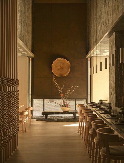 安缦纽约酒店宽敞浴室，米色大理石墙面，圆形铜镜，现代简约设计。