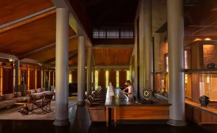 Amanoi resort bar with wooden columns, warm lighting, and seating areas at dusk.