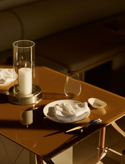 Akari dining venue at Amanzoe, featuring a table setting with a glass of water and plate against warm wooden tones.