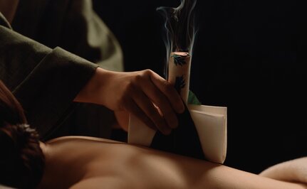 安缦伊沐度假村的艾草疗法治疗,施者将温热的艾草应用于客人背部。