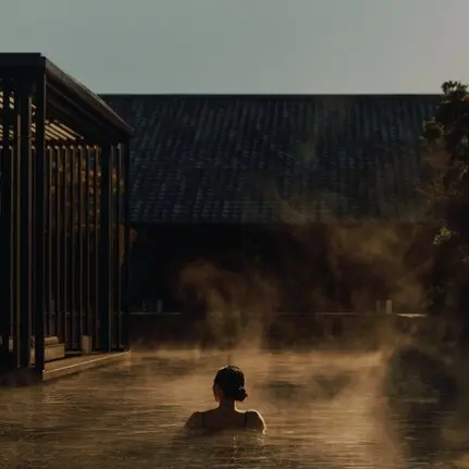 Pessoa a banhar-se num onsen ao amanhecer no resort Amanemu, Japão.