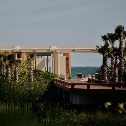 Beachfront casita at Amanvari with ocean views beyond palm trees and coastal vegetation.